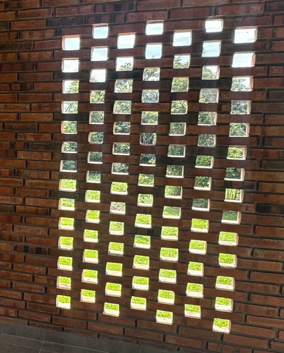 Muro de celosía de ladrillo con la luz de afuera entrando por los huecos.